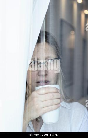 Blonde Frau, die aus dem Fenster schaut, Mailand, Italien. Stockfoto