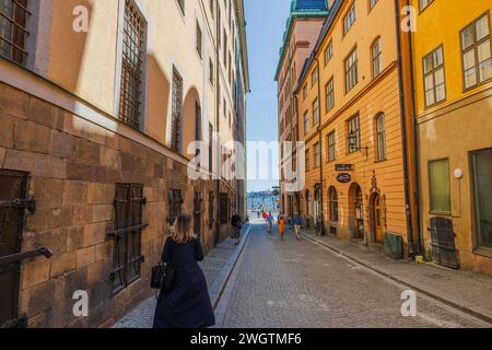 Blick auf eine enge gepflasterte Touristenstraße in Gamlastan, Stockholm, die zum Ufer des Flusses führt. Schweden. Stockholm. Stockfoto