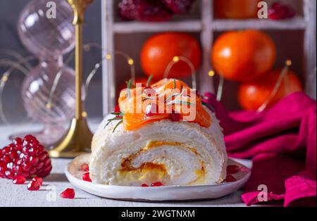 Meringue-Rolle gefüllt mit Mascarpone, Sahne und Mandarinenmarmelade, dekoriert mit Mandarinen und Granatapfelkernen. Stockfoto