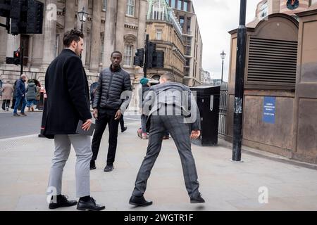 Ein junger Mann übt am 6. Februar 2024 in London, dem Finanzviertel der Hauptstadt, hohe Kicks vor Arbeitskollegen. Stockfoto