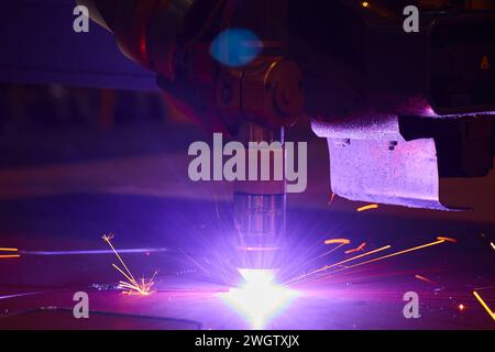 Industrielle Laserschneidemaschine und Funkenparks in Aktion Stockfoto