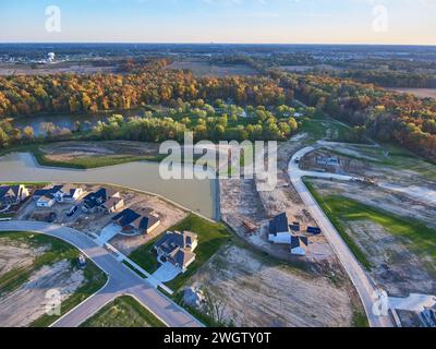 Blick aus der Vogelperspektive auf die Bauarbeiten in den Vorstädten bei der Golden Hour mit Herbstbäumen Stockfoto