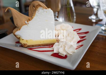 Key Lime Pie auf einem Teller mit Schlagsahne und rotem Niesel schneiden Stockfoto