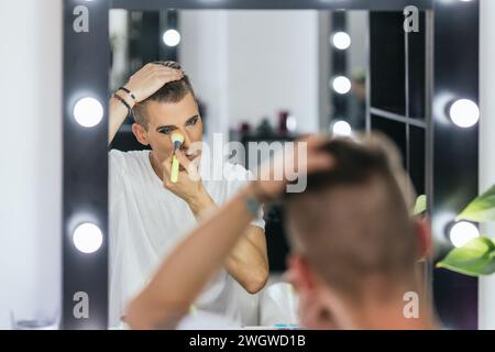 Schwuler Mann, der sich mit einer Bürste in einer Backstage ausdenkt Stockfoto