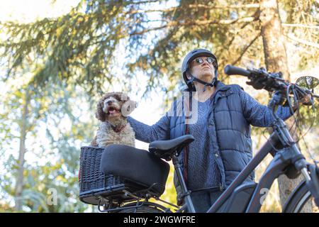 Ältere Frau und ihr Hund genießen die Natur auf dem Elektrofahrrad Stockfoto