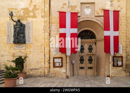 Birgu (Vittoriosa), Malta - 14. September 2022: Die Flagge des Heiligen Johannes hing an beiden Seiten der Tür zur Stiftskirche des Heiligen Lorenz. Stockfoto