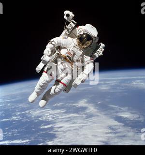 S84-27562 (7. Feb. 1984) --- Astronaut Bruce McCandless II, der an einer historischen außerfahrbaren Aktivität (EVA) teilnimmt, befindet sich in diesem 70-mm-Rahmen nur wenige Meter von der Kabine des erdumkreisenden Space Shuttle Challenger entfernt. Diese Extravehicle Activity (EVA) stellte den ersten Einsatz einer mit Stickstoff betriebenen, handgesteuerten Vorrichtung dar, die Manned Manövering Unit (MMU) genannt wird, die eine viel größere Mobilität ermöglicht, als die früheren Weltraumläufer, die restriktive Haltegurte verwenden mussten. Robert L. Stewart hat später die MMU ausprobiert, die McCandless hier benutzt. Stockfoto