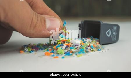 Makroaufnahme von Fingern, die Mikroplastikpartikel aus einem Mini-Plastikmüll entnehmen. Das Konzept der Wasserverschmutzung und der globalen Erwärmung. Makroaufnahme mit Stockfoto