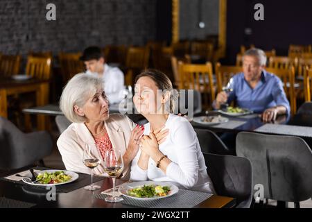 Ältere Frau tröstet weinende junge Freundin im Restaurant Stockfoto