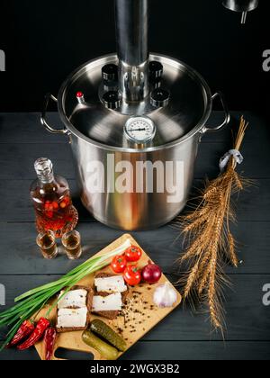 Mondschein immer noch auf schwarzem hölzernem Hintergrund. Alkohol in einer Glaskaraffe. Snack auf dem Schneidebrett. Stockfoto