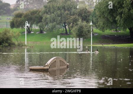 Unterer Spielplatz und großer Teich im Polliwog Park, überflutet vom Regen in Manhattan Beach, CA Stockfoto