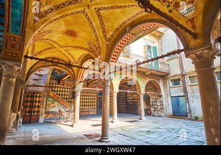 CREMONA, ITALIEN - 6. APRIL 2022: Die mit Fresken geschmückte Arkade mit Steinsäulen und Rippengewölbedecke im Innenhof des mittelalterlichen Palazzo an der Via Palestro, C. Stockfoto