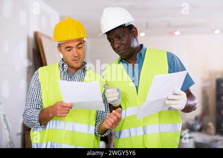 Bauherren mit Gespräch über den Arbeitsplan in der Wohnung Stockfoto