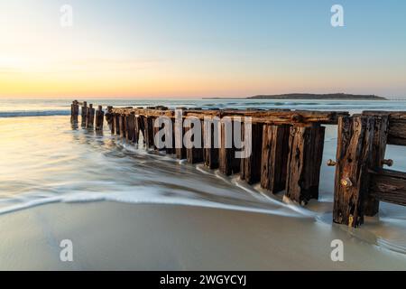 Die Victor Harbor Erosion Groyne mit einer langen Exposition und Granitinsel im Hintergrund und pastellfarbenen Himmel in South Australia am 11. September 2023 Stockfoto