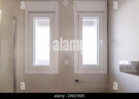 Weiße Doppelfenster aus Aluminium in einem Badezimmer neben einer Duschkabine Stockfoto