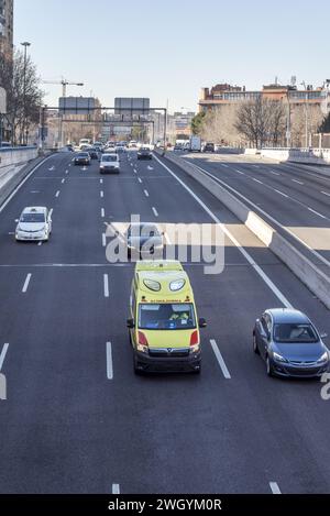 Ein Krankenwagen fährt mit Warnleuchten auf einer vierspurigen Autobahn Stockfoto