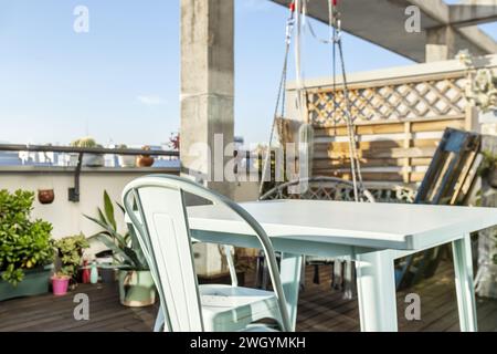 Eine urbane Terrasse mit Pflanzen und einem Metalltisch mit passenden Stühlen und Blick auf die Stadt Stockfoto