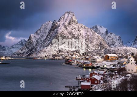 Das Fischerdorf reine und der Berg Olstinden bei Sonnenaufgang im Winter, Gemeinde Moskenes, Nordland County, Lofoten Inseln, Norwegen Stockfoto