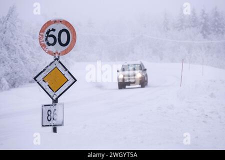 Auto, das 60 km/h und Priority-Straßenschilder bei eisigen Fahrbedingungen auf einer Autobahn in Senja, Norwegen, Skandinavien, Europa überquert Stockfoto