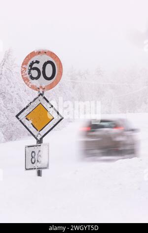 Rasantes Auto, das 60 km/h und Priority-Straßenschilder bei eisigen Fahrbedingungen auf einer Autobahn in Senja, Norwegen, Skandinavien, Europa überquert Stockfoto