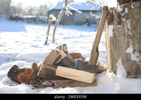 Metallaxt und Holzhaufen im Freien an sonnigen Wintertagen Stockfoto