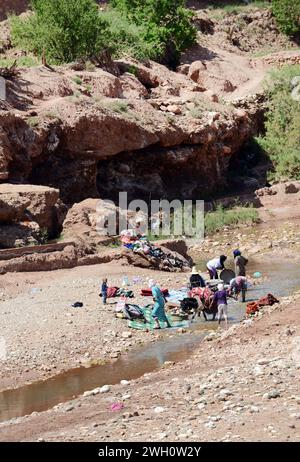 Lokale Berberfrauen waschen Kleidung am Asif Ounila Fluss bei Ksar von Ait-Ben-Haddou in Marokko. Stockfoto