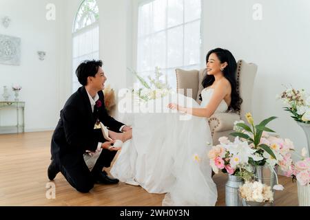 Ein hingebungsvoller Bräutigam hilft seiner Braut mit Schuhen, einer sanften Geste der Liebe und Unterstützung Stockfoto