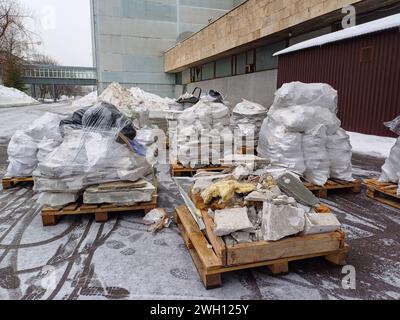 In Zellophanfolie verpackte Bauabfälle liegen im Freien auf Holzpaletten. Stockfoto