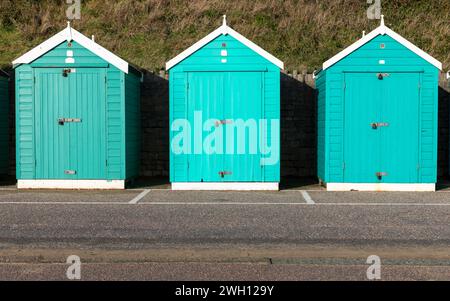 Drei Strandhütten in Aqua Blau an einer Promenade in Dorset. An einem sonnigen Dezembernachmittag. Teil einer Serie. Stockfoto