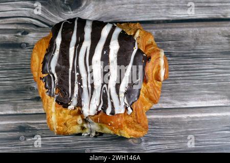 Gebackenes dänisches Gebäck, gefüllt mit brauner Zartbitterschokolade und weißer Schokoladensauce, süßer Backteig, der im Ofen mit Mehl, Zucker und gebacken wird Stockfoto