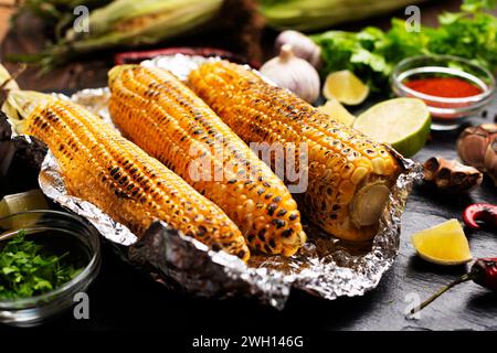 Gegrillter Mais auf dem Kolben in Zinnfolie auf Küchentisch gesundes glutenfreies Essen Hintergrund Stockfoto