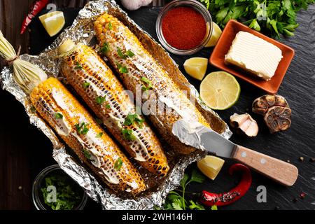 Gegrillter Zuckermais mit geräucherter Paprika Limette und Butter in Alufolie auf Küchentisch gesunder glutenfreier flacher Lay Food Hintergrund Stockfoto