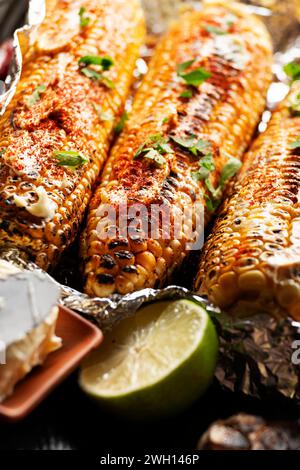 Gegrillter Zuckermais mit geräucherter Paprika Limette und Butter in Alufolie auf Küchentisch glutenfreie gesunde Lebensmittel Hintergrund Stockfoto