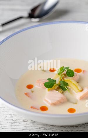 Lachssuppe auf einem weißen Porzellanteller mit Salat an der Seite Stockfoto