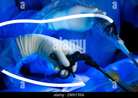 Nahaufnahme der Hand eines Chirurgen, der ein laparoskopisches Instrument mit hellem Neonlicht bedient. Selektiver Fokus. Stockfoto