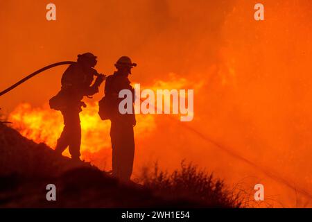 Thomas Fire, Ventura, CA, Los Padres NF, 2017 zwei Feuerwehrleute bekämpfen die Flammen vor einem leuchtend orangen Hintergrund des gewaltigen Waldbrandes Stockfoto