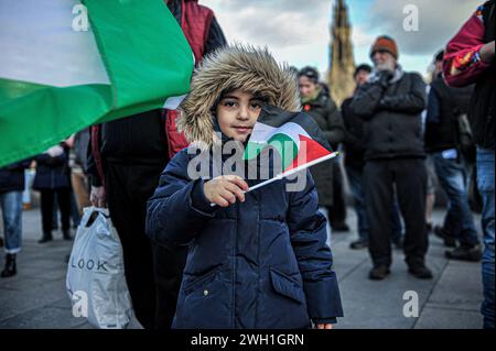 Edinburgh, Großbritannien. Januar 2024. Ein kleines Kind wird auf dem Hügel stehen gesehen, während es während der Demonstration eine palästinensische Flagge schwenkt. Pro-Palestine-Anhänger hielten eine Kundgebung in Edinburgh am Mound ab, wo die Menge den Rednern zuhörte und Unterstützung zeigte. Während der Kundgebung eine Liste, die auf Stoff geschrieben wurde, mit einer kleinen Liste unschuldiger Zivilisten, die im Konflikt von israelischen Streitkräften getötet wurden. Die Kundgebung wurde zu einem marsch, der am Mound begann und dann die Princes Street hinunter und dann auf den Charlotte Square ging, bevor sie aus Bute House, dem Heim des ersten Ministers o, endete Stockfoto