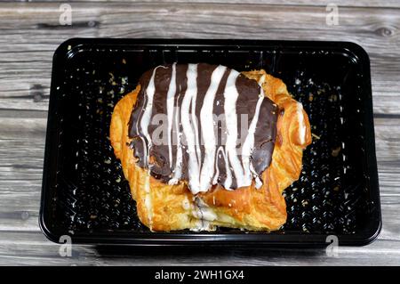 Gebackenes dänisches Gebäck, gefüllt mit brauner Zartbitterschokolade und weißer Schokoladensauce, süßer Backteig, der im Ofen mit Mehl, Zucker und gebacken wird Stockfoto