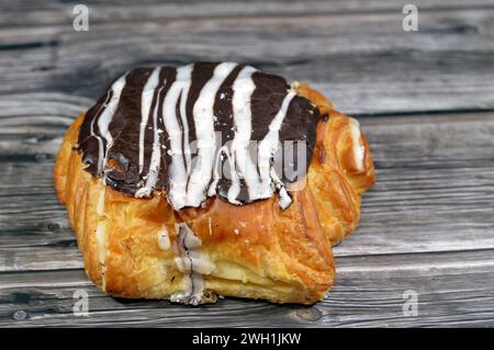 Gebackenes dänisches Gebäck, gefüllt mit brauner Zartbitterschokolade und weißer Schokoladensauce, süßer Backteig, der im Ofen mit Mehl, Zucker und gebacken wird Stockfoto