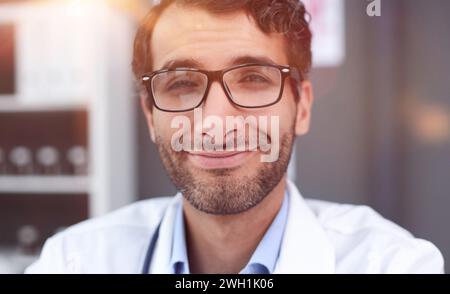 Selbstbewusster männlicher Arzt in Brille, der aus der Nähe lächelt Stockfoto