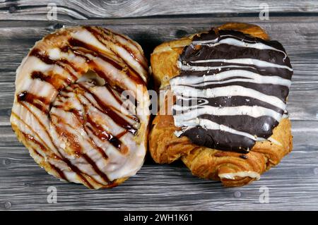 Dänisches Gebäck gefüllt und garniert mit brauner dunkler Schokolade, weißer Schokolade, Karamellsauce, süßem Backteig im Ofen mit Mehl, Zucker und Stockfoto