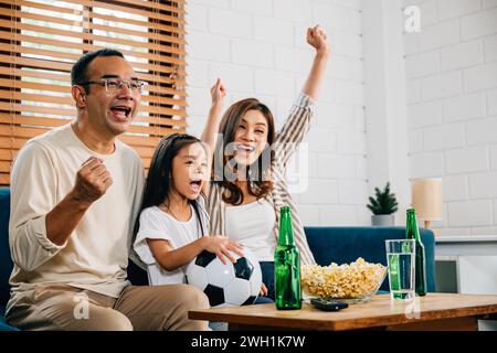 Eine glückliche Familie genießt den Nervenkitzel eines Fußballspiels zu Hause Stockfoto