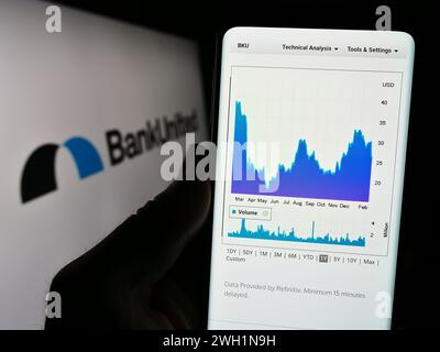 Person mit Smartphone und Webseite des US-Finanzdienstleisters BankUnited Inc. Vor dem Logo. Konzentrieren Sie sich auf die Mitte des Telefondisplays. Stockfoto