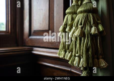 Schöne grüne Vorhangembrasse mit Quaste. Dekoratives Stück, das die Vorhänge dank eines eleganten Knotens ordentlich zusammenhält Stockfoto