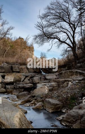 Das halbtrockene Flussbett und das stagnierende Wasser des Flusses Ter, der an Montesquiu in der Provinz Barcelona im Norden Kataloniens vorbeifließt. Der Ter ist ein katalanischer Fluss, der in den Pyrenäen entspringt und in das Mittelmeer mündet. Die Dürre, unter der Katalonien seit 2021 leidet, hat dazu geführt, dass die Flussrate und die ökologische Qualität der Flüsse zurückgegangen sind, was sich negativ auf die biologische Vielfalt des Gebiets auswirkt. zwar bleiben die Einleitungen aus Kläranlagen und Industriezweigen in den Fluss gleich, aber die Schadstoffe können nicht d sein Stockfoto