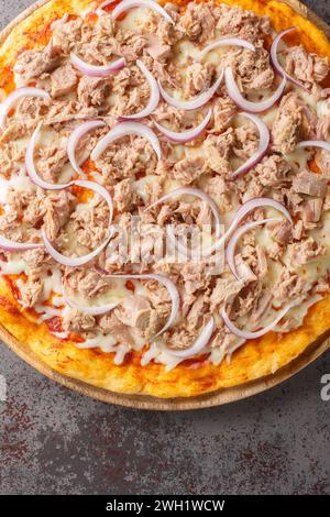 Leckere Nahaufnahme von italienischer Zwiebeln- und Thunfischpizza auf dem Holzbrett auf dem Tisch. Vertikale Draufsicht von oben Stockfoto