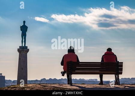 Zwei Freunde draußen an einem schönen sonnigen Tag, sitzen auf der Bank der Kalemegdan-Festung in Belgrad, mit wunderschönem Blick auf die Siegesstatue (Pobednik) Stockfoto