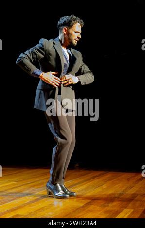 'Männlicher Flamenco-Tänzer mit intensivem Ausdruck auf einer Holzbühne, gekleidet in einem klassischen Anzug.' Stockfoto