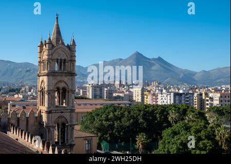 Eine majestätische Kathedrale von Palermo steht hoch inmitten einer atemberaubenden Landschaft mit Bäumen, Bergen und der belebten Stadt palermo, italien, mit ihren hohen Türmen Stockfoto