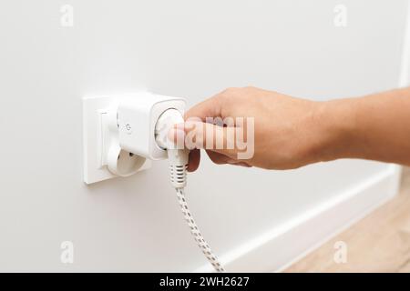 Der Mann verwendet eine Steckdose, einen intelligenten Stecker in die Steckdose. Kontrolle der Stromkosten Stockfoto